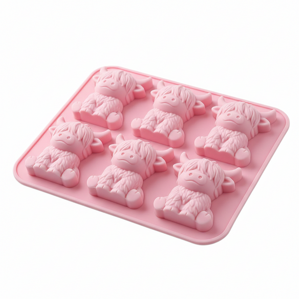 A pink silicone mold tray featuring six individual cavities shaped like cute highland cows, shown on a clean white background.